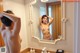 A naked woman standing in front of a mirror in a bathroom.