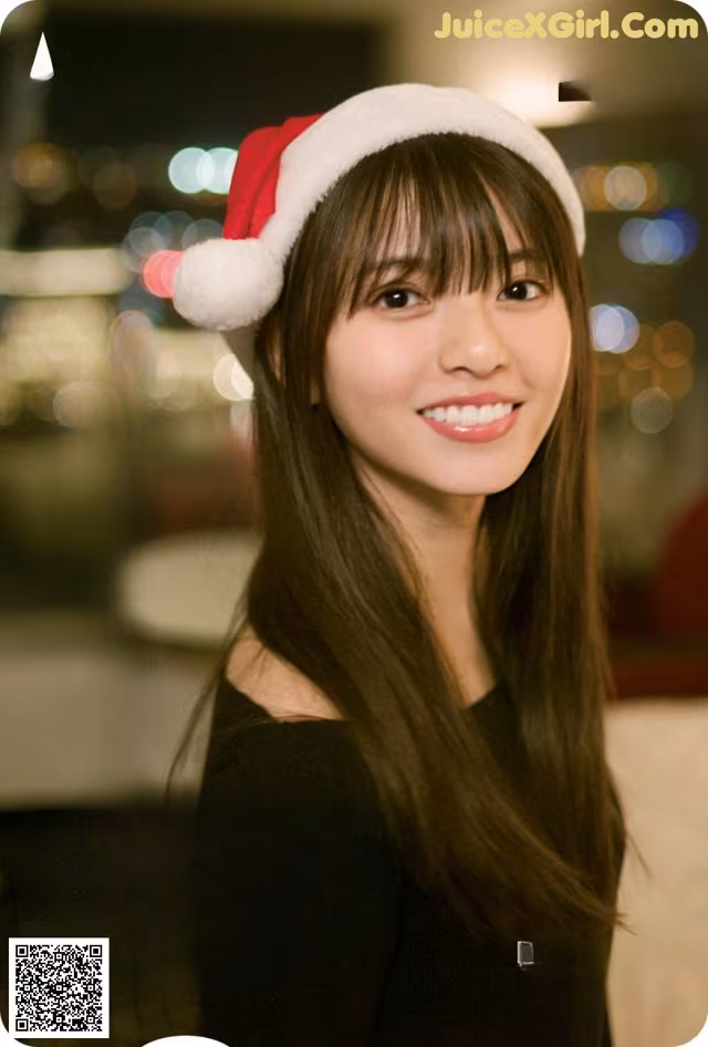 A woman wearing a santa hat smiles at the camera.