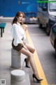 A woman sitting on a bench in a parking lot.