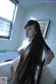 A woman with long black hair standing in a bathroom.