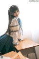 A woman in a school uniform sitting at a desk.