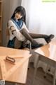 A woman in a school uniform sitting at a desk.