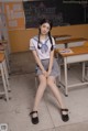 A woman in a school uniform sitting on a chair in a classroom.