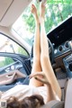 A woman laying in the driver's seat of a car with her feet up.