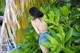 A woman in a black top and blue shorts standing in front of a palm tree.