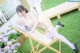 A woman in a white lingerie sitting on a wooden chair.