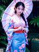 A woman in a blue and pink kimono holding an umbrella.