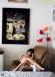 A woman sitting on a brown chair in a bedroom.