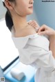 A woman in a white shirt is putting on a white hat.