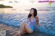 A woman in a pink bathing suit sitting in the ocean.