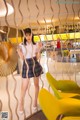 A woman standing in front of a yellow chair.