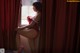 A woman in a red lingerie sitting on a window sill.