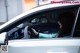 A woman driving a white car with a hello kitty on the dashboard.