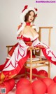 A woman in a red and white dress sitting on a chair.