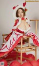 A woman in a red and white outfit sitting on a chair.