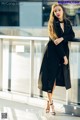 A woman in a black coat leaning against a railing.