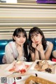 Two young women sitting at a table with plates of food.