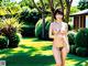 A naked woman standing in the middle of a lush green field.