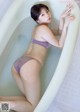 A woman in a purple bikini sitting in a bathtub.