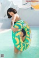 A woman in a bikini holding an inflatable banana ring in a pool.