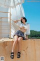 A woman in a sailor outfit sitting on a wall.