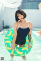 A woman in a bathing suit holding an inflatable ring in a pool.