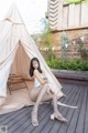 A woman sitting in front of a teepee on a wooden deck.