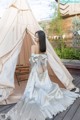 A woman in a wedding dress standing in front of a teepee.