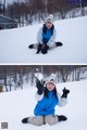 A woman sitting in the snow with her hands in the air.