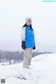 A woman standing on top of a snow covered hill.