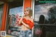 A woman standing in front of a store talking on a cell phone.