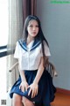 A woman in a school uniform sitting on a chair.