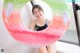 A woman in a bathing suit holding an inflatable donut.