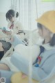 Two young women sitting on a swing reading a book.