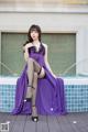 A woman in a purple dress sitting by a pool.