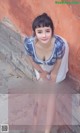 A woman in a blue and white dress leaning against a wall.