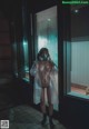 A naked woman wearing a gas mask standing in a bathroom.