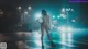 A woman in a white raincoat standing on a crosswalk at night.