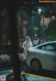 A woman wearing a face mask standing next to a car in the rain.