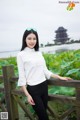 A woman standing on a wooden bridge in front of a lake.