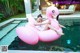 A woman laying on an inflatable flamingo floating in a pool.